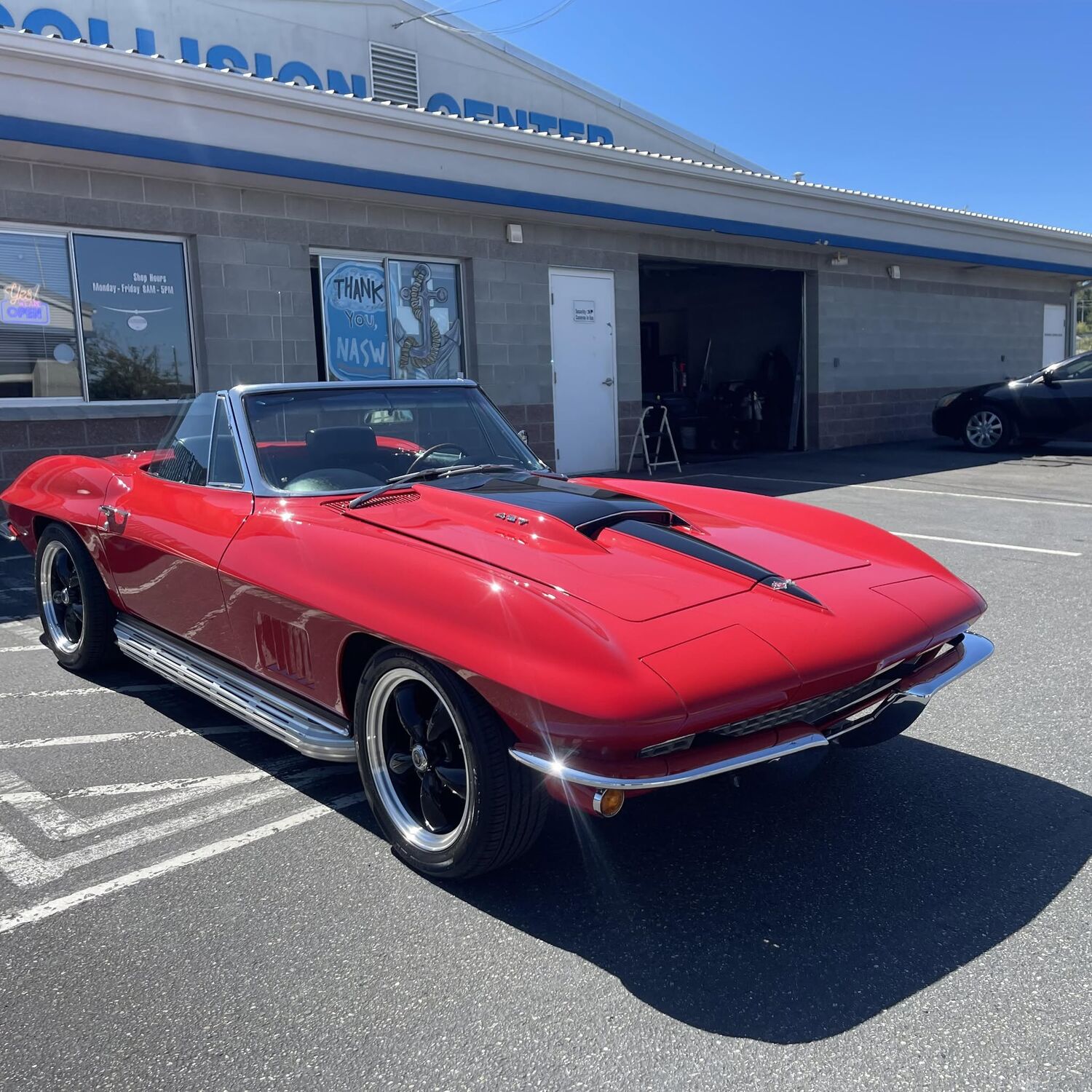 Red classic Corvette convertible with a black hood stripe, freshly detailed outside the shop