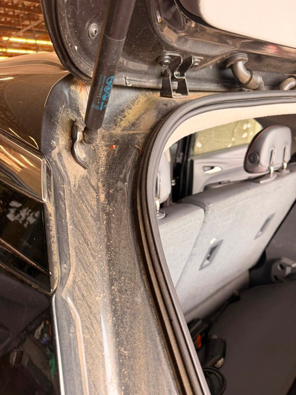 Hatch jamb of a car caked in sand and grit before detailing